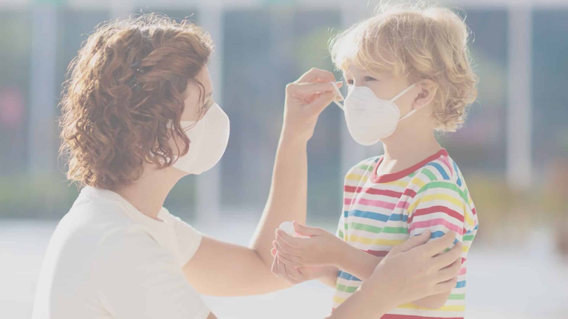 Mother Helping Child Put On A Mask