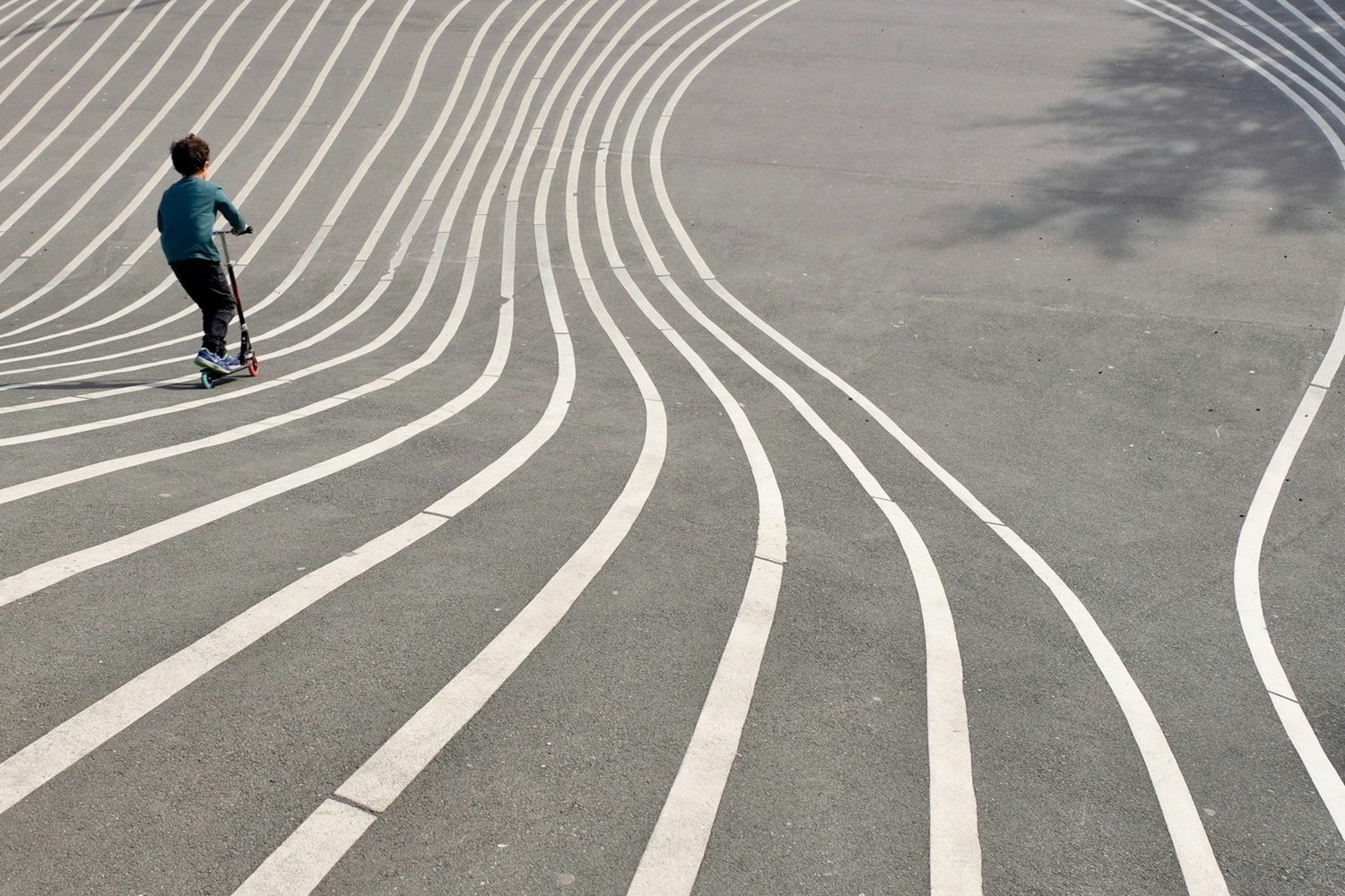 boy playing kick scooter on gray concrete pavement