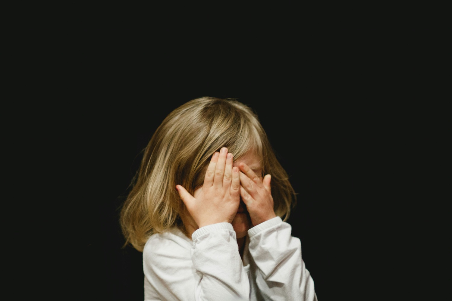 Girl hiding behind hands