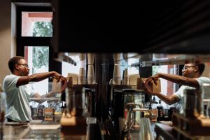 barista putting beans into espresso machine with reflection