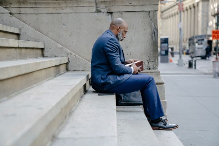 man sitting on urban steps holding a notebook