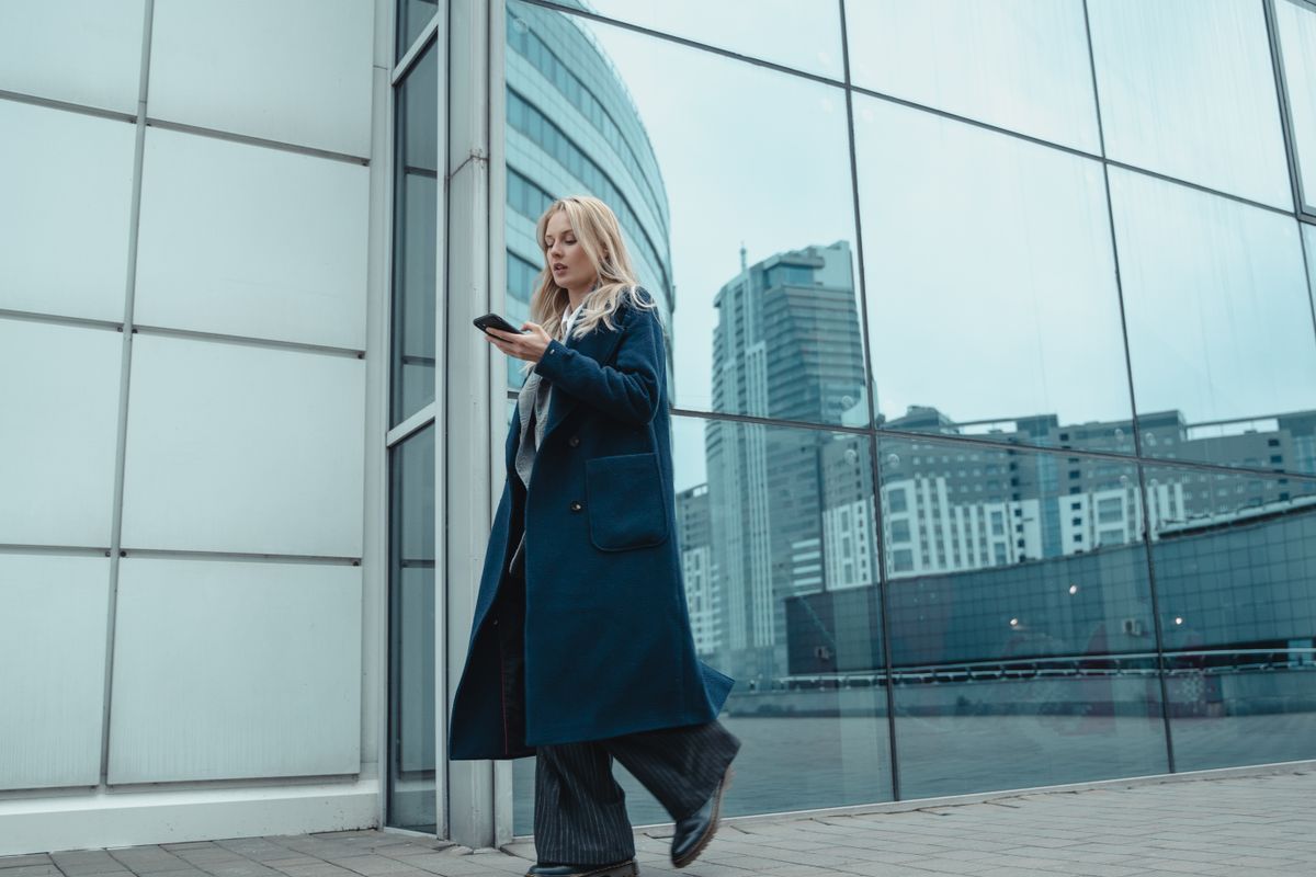 woman walking by glass wall with urban reflections