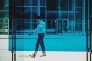 Professional man walks while on a phone call outside a modern glass building