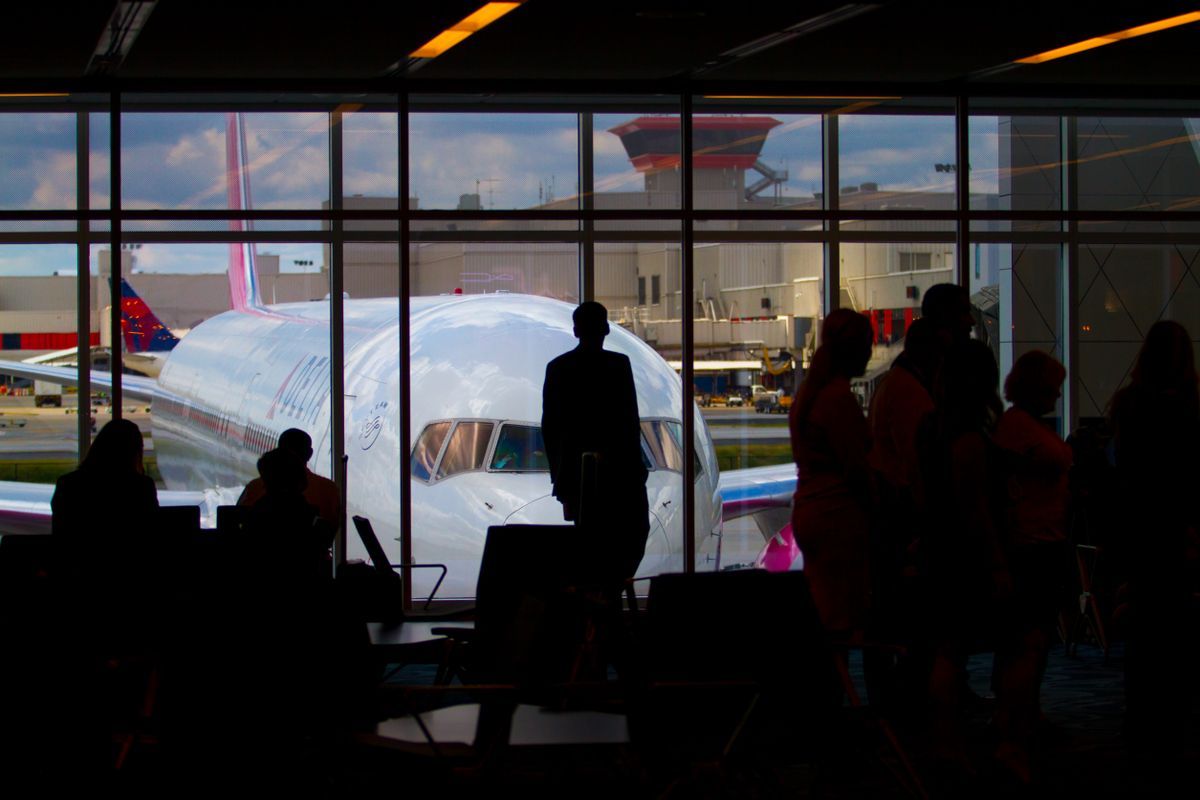 Silhouettes of travelers waiting at an airport terminal